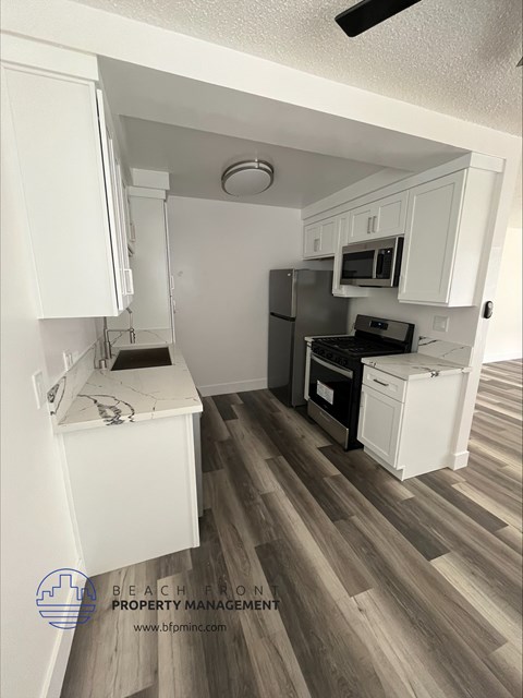 a small kitchen with white cabinets and a stove and refrigerator